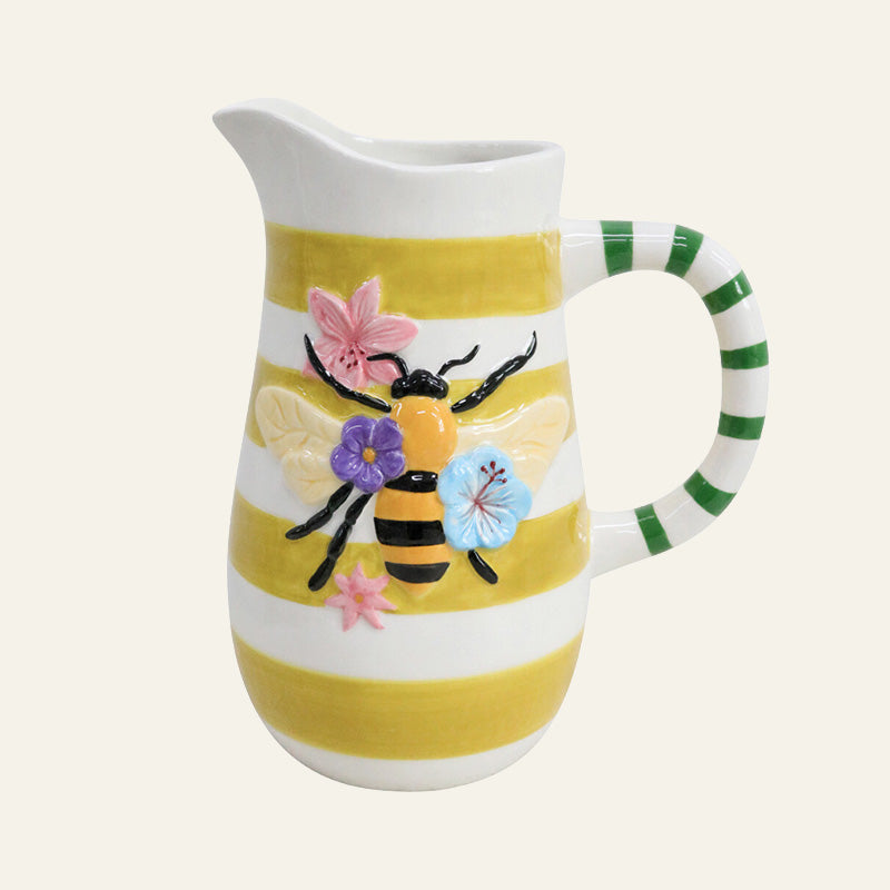 Ceramic jug with yellow and white stripes, green striped handle, and raised bee with flower detail on the front.