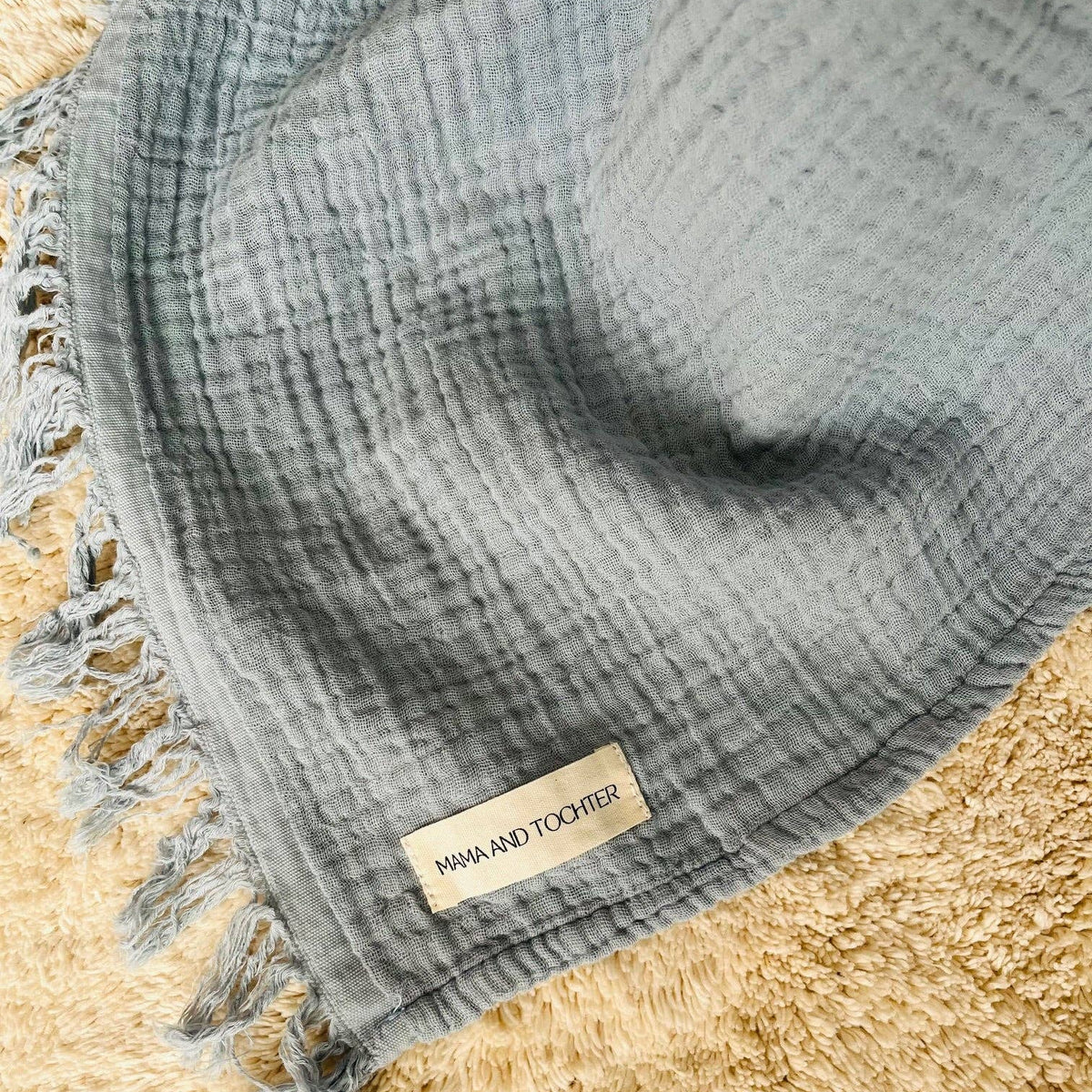 Close-up of dusty blue cotton muslin fabric with delicate fringed edging