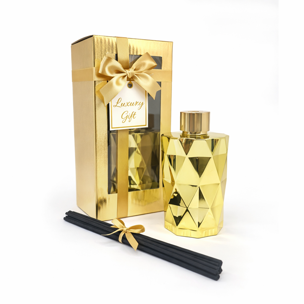 Gold gift set with a diamond-patterned bottle, packaging, and black sticks on a white background.