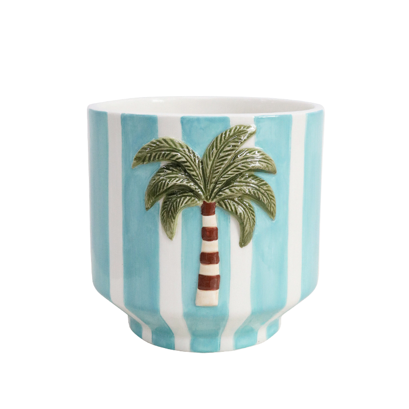 Ceramic plant pot holder with a palm tree design on a blue and white striped background