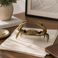 Bronze crab sculpture on a stack of papers with a blurred background
