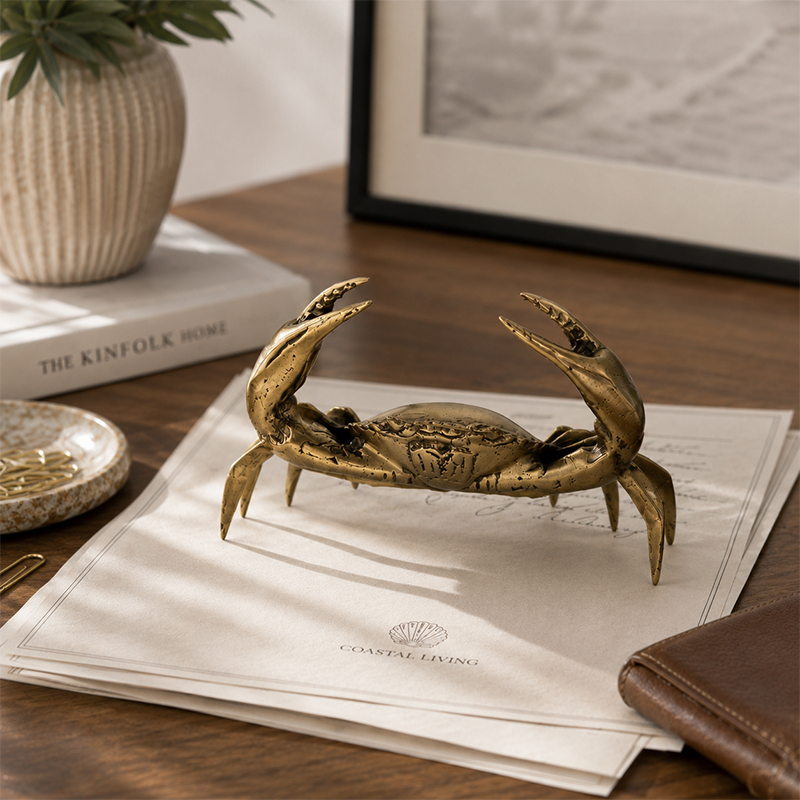Bronze crab sculpture on a stack of papers with a blurred background