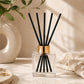 Kairo Reed diffuser with black sticks in a clear square container with gold cap 