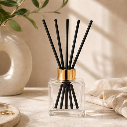 Kairo Reed diffuser with black sticks in a clear square container with gold cap 