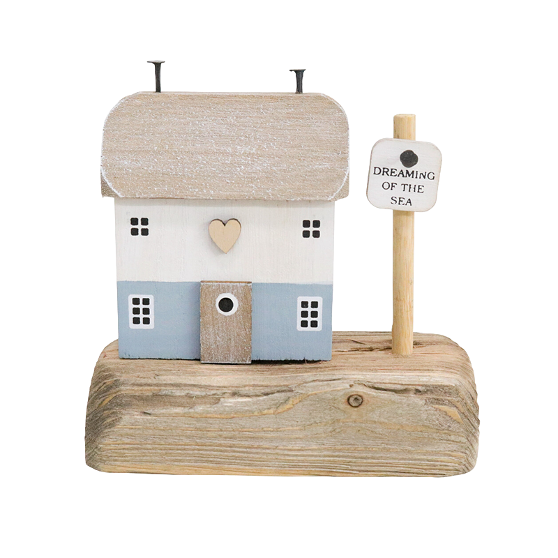 Decorative house on a wooden base with a sign reading 'Dreaming of the Sea' 