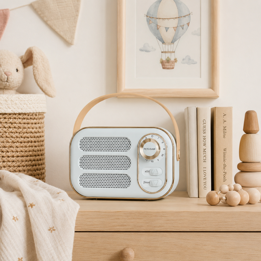 Blue 1960s-inspired Bluetooth speaker with tan carry handle, front speaker grille and gold-tone dial placed in baby's nursery