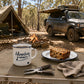 Adventure Continues mug with coffee, fruit cake and folding pliers at an Australian bush campsite