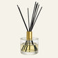 Luxury Aria Reed diffuser with black sticks in a clear glass bottle with a long gold cap 