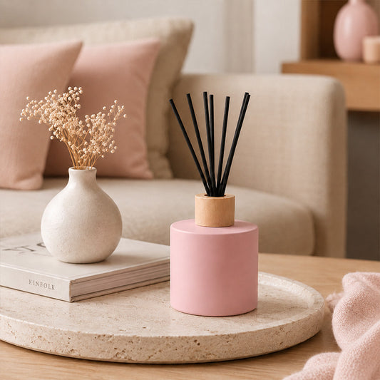 Pink diffuser with black reeds on a stone tray in a living room setting