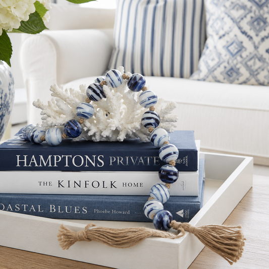 Decorative setup with books, coral, and beads on a tray in a home setting.