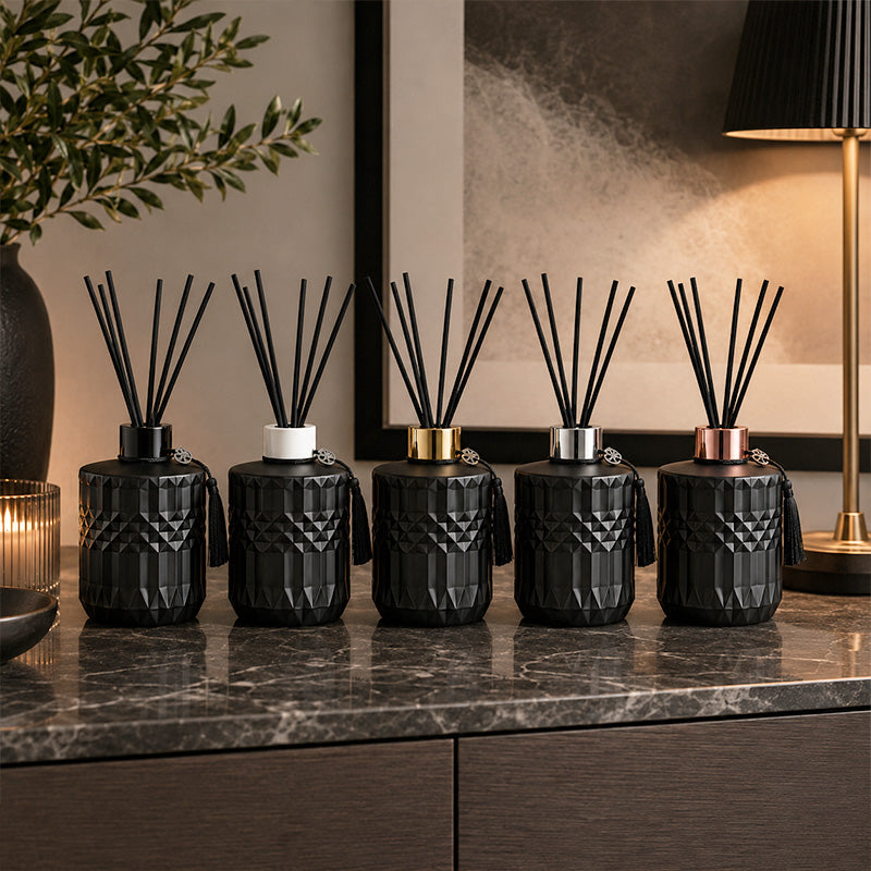 Set of black textured diffusers on a marble surface with decorative elements.