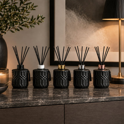Row of black diffusers on a marble surface with decorative elements.