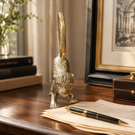 Gold solid brass monkey sculpture in a crouching pose with a curled tail sat on desk