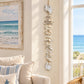 A vertical hanging driftwood wall decor piece made of stacked natural white and beige wood pieces, with a small star-shaped hanging ornament at the bottom, shown on a plain white background.