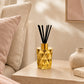 Gold geometric diffuser on a wooden side table with a neutral-colored sofa and decor in the background