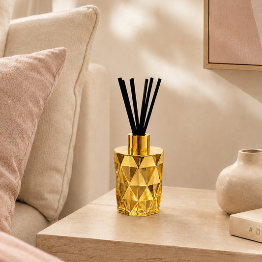 Gold geometric diffuser on a wooden side table with a neutral-colored sofa and decor in the background