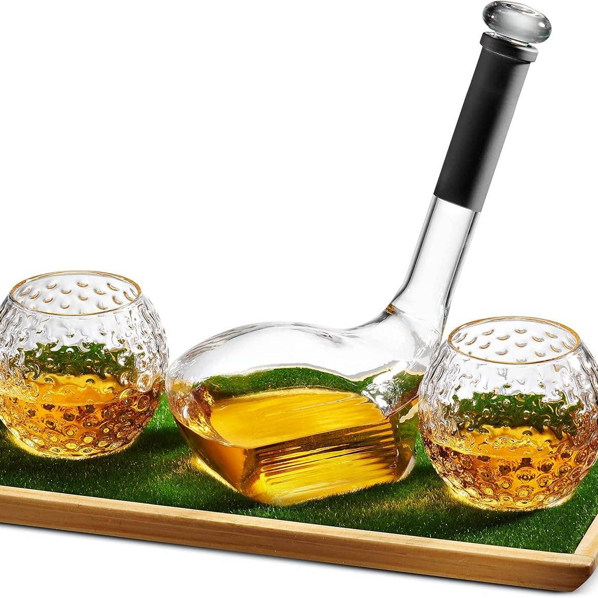 A clear glass decanter with a black handle and two textured glass tumblers, arranged on a green mat inside a rectangular wooden tray. 