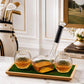 Two glasses filled with whisky and a decanter on a tray with a golf theme in the background.