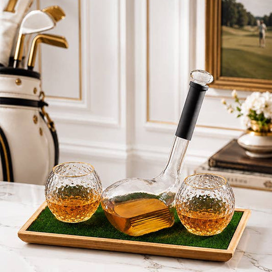 Two glasses filled with whisky and a decanter on a tray with a golf theme in the background.