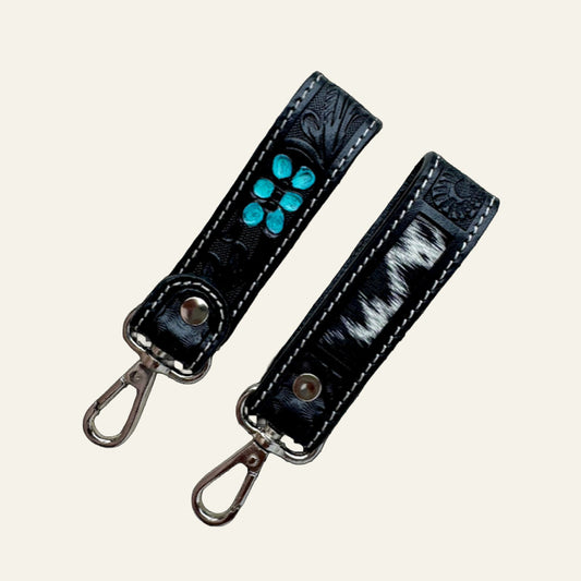 Double-sided black leather keyring with turquoise hand-painted tooling and a black-and-white cowhide panel.