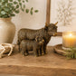 Antique bronze Highland Cow and Calf Figurine with detailed textured shaggy coats on a wooden shelf with candel, beaded garland, vase and plant
