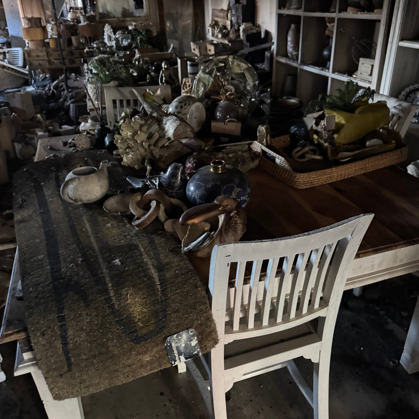 Damage after fire of a shop interior -  table and chairs, surrounded by various items and furniture.