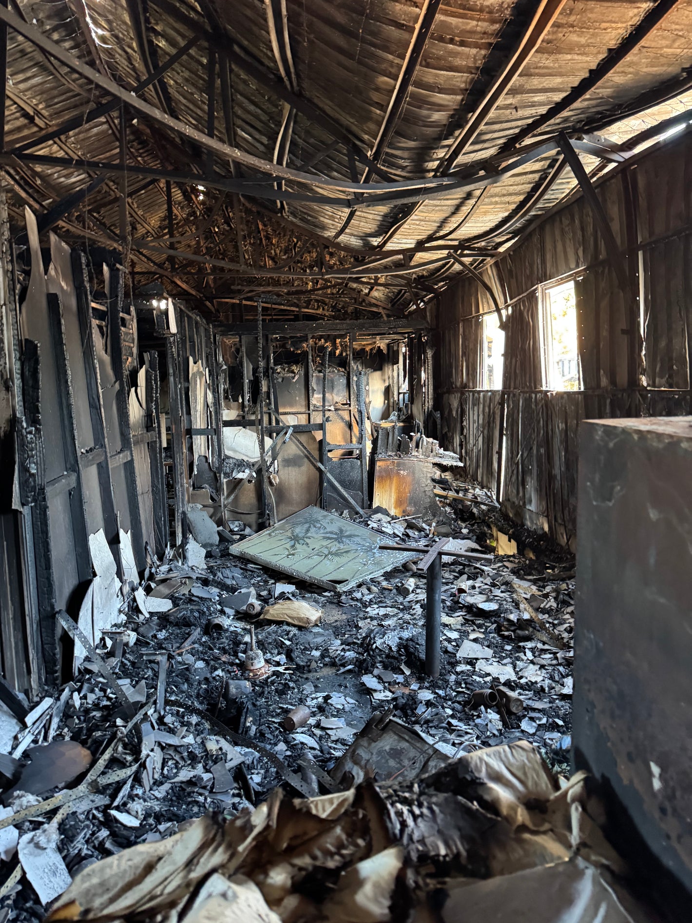 Burnt and charred interior of a building with debris and twisted metal.