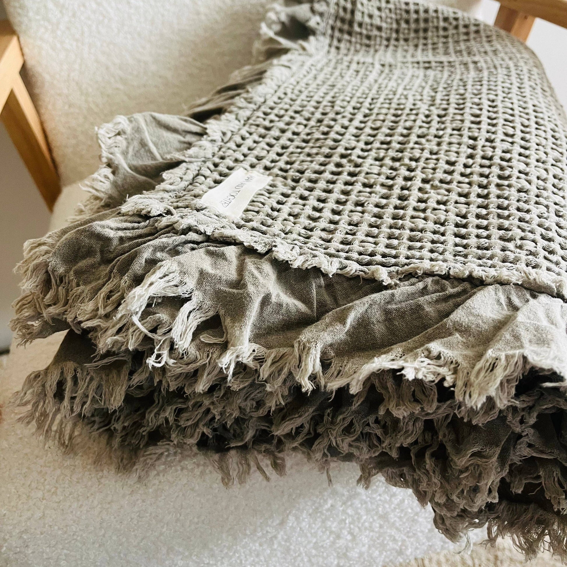 Add earthy colour and relaxed texture with this khaki waffle throw blanket, made from organic cotton and finished with soft frayed ruffle edging.