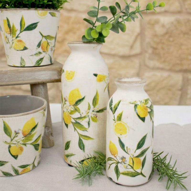 Decorative bud vases with lemon and leaf patterns on a table.