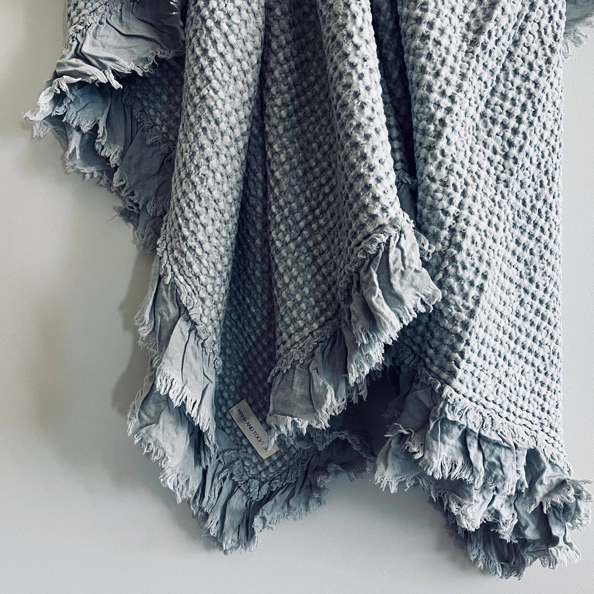 Close-up of the light grey waffle weave and softly frayed ruffle edge