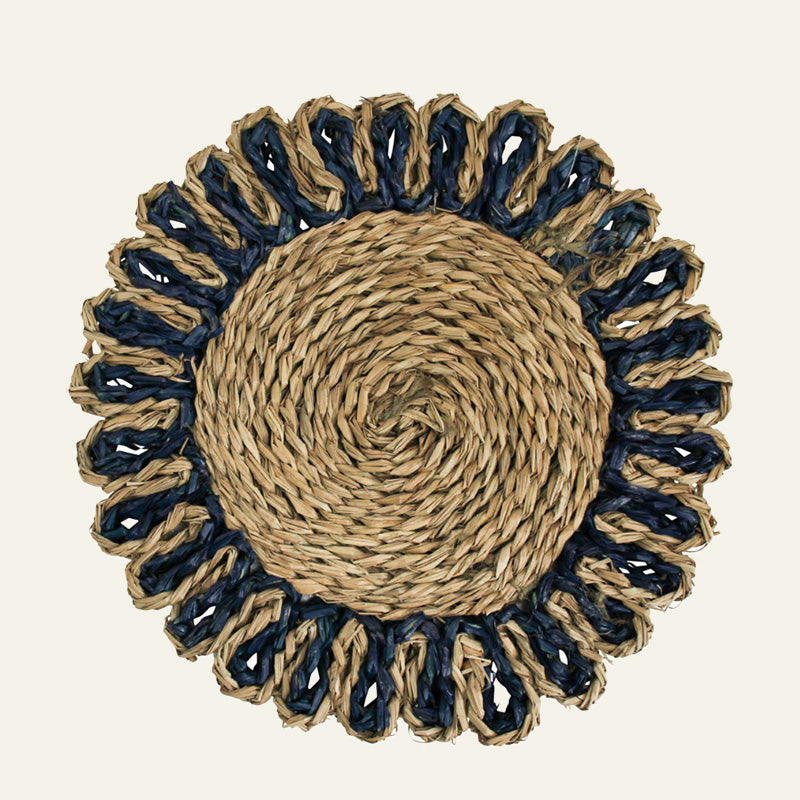 Round woven placemat with natural and navy border on beige background