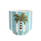 Ceramic plant pot holder with a palm tree design on a blue and white striped background