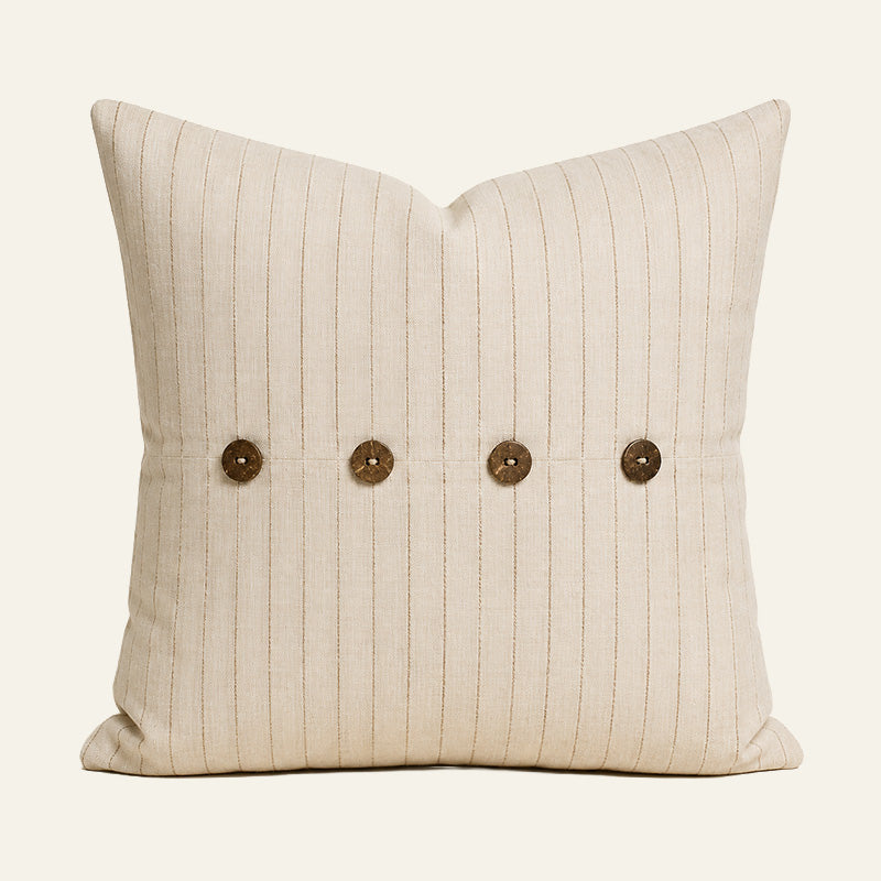 Tan pinstripe French linen cushion cover with four coconut buttons on a warm ivory background.