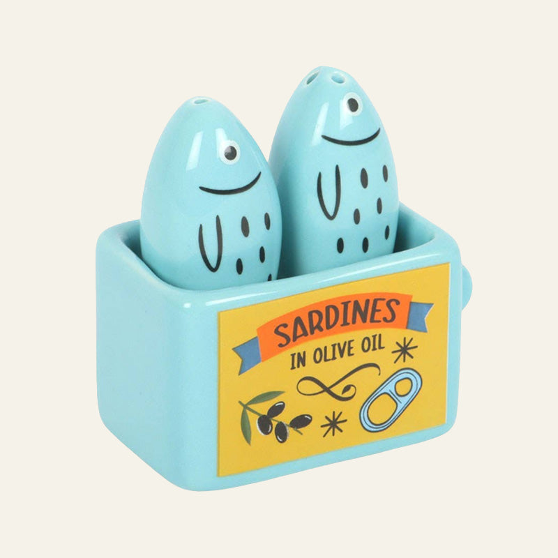 Blue sardine shaped salt and pepper shakers in a holder with a 'Sardines in Olive Oil' label 