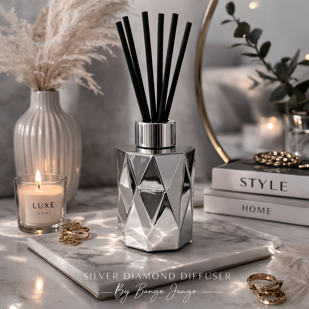 Silver diamond diffuser with candles and books on a marble surface