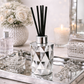 Crystal diffuser with black sticks on a decorative tray with candles and flowers