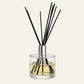Luxury Aria Reed diffuser with black sticks in a clear glass bottle with a long gold cap 