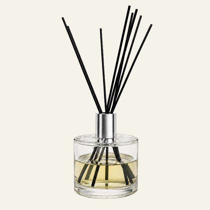Luxury Aria Reed diffuser with black sticks in a clear glass bottle with a long gold cap 