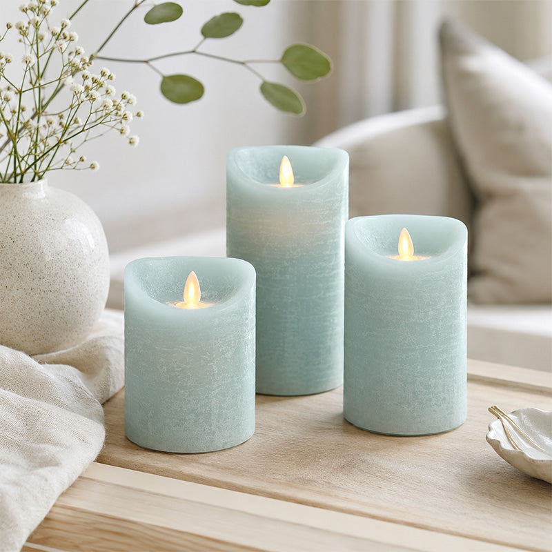 Set of three light blue candles on a wooden surface with a blurred background