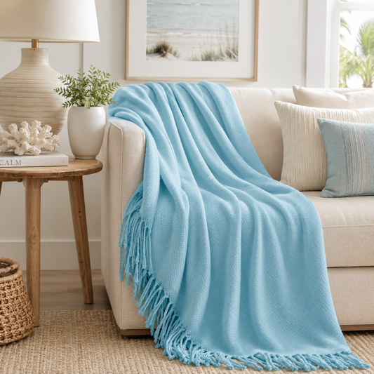 Light blue throw blanket draped over a beige sofa in a living room setting.