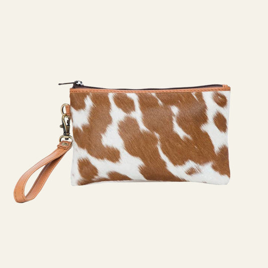 Small tan and white cowhide clutch with a detachable leather wrist strap and top zip.