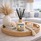 Candle labeled 'Sunburst' on a decorative tray with a diffuser and decor items in a living room setting.