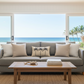 Living room with a gray sofa, coffee table, and large windows overlooking a beach.