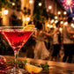 Cocktail with garnishes on a wooden table with people and fireworks in the background