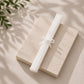 White diffuser Reed sticks on a light stone surface with green leaves in the corner