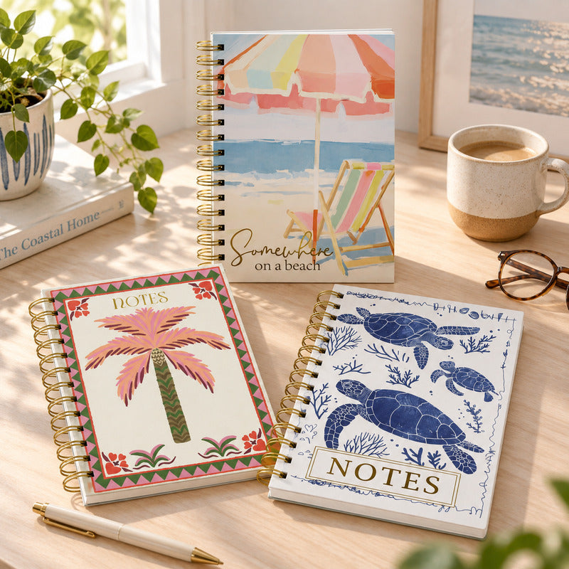 Three A5 gold spiral notebooks featuring beach chair, tropical palm and sea turtle cover designs.
