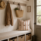 Nook with coat, bag, and striped pillow on a bench with storage baskets.