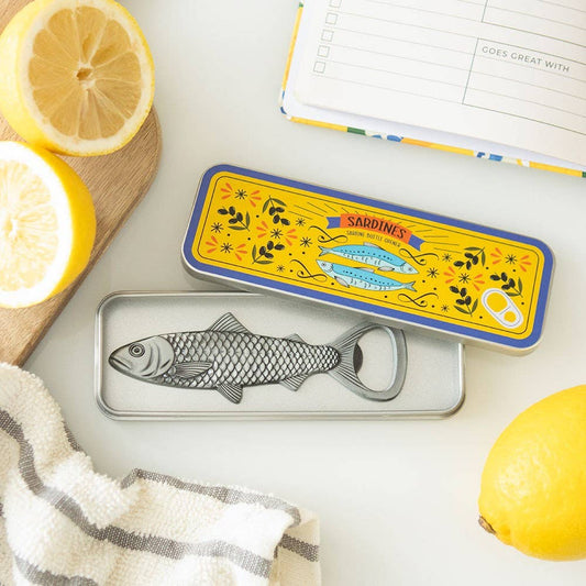 Sardine bottle opener in sardine storage tin surrounded by lemons and a recipe planner