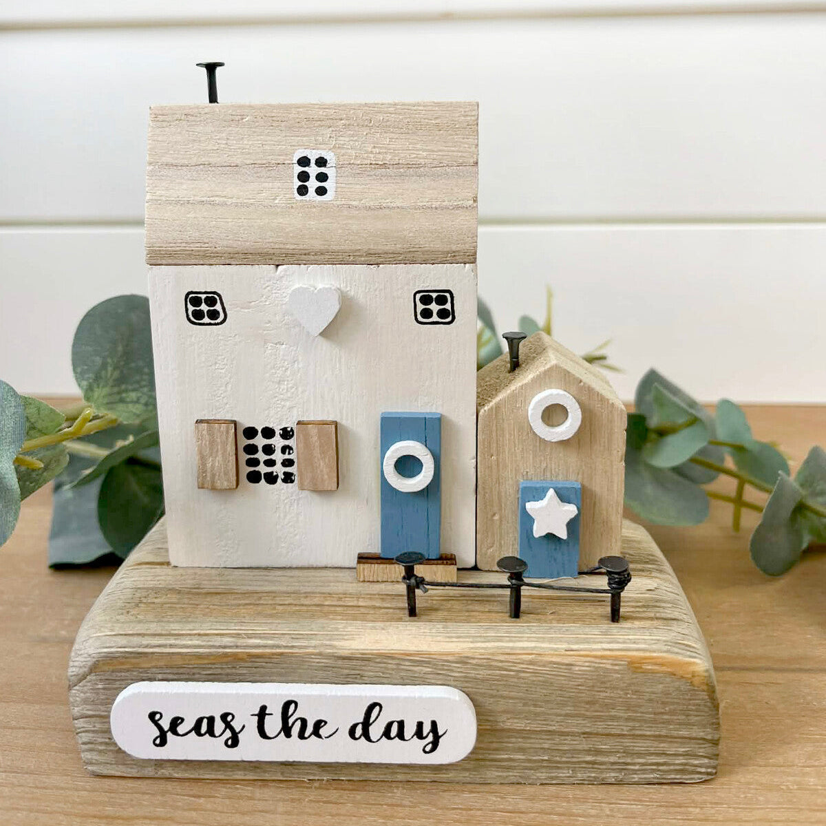 Decorative wooden house sculpture with 'seas the day' text on a white background