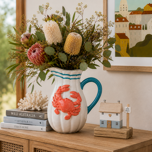 Decorative vase with a crab design on a wooden surface with a floral arrangement and books in the background.